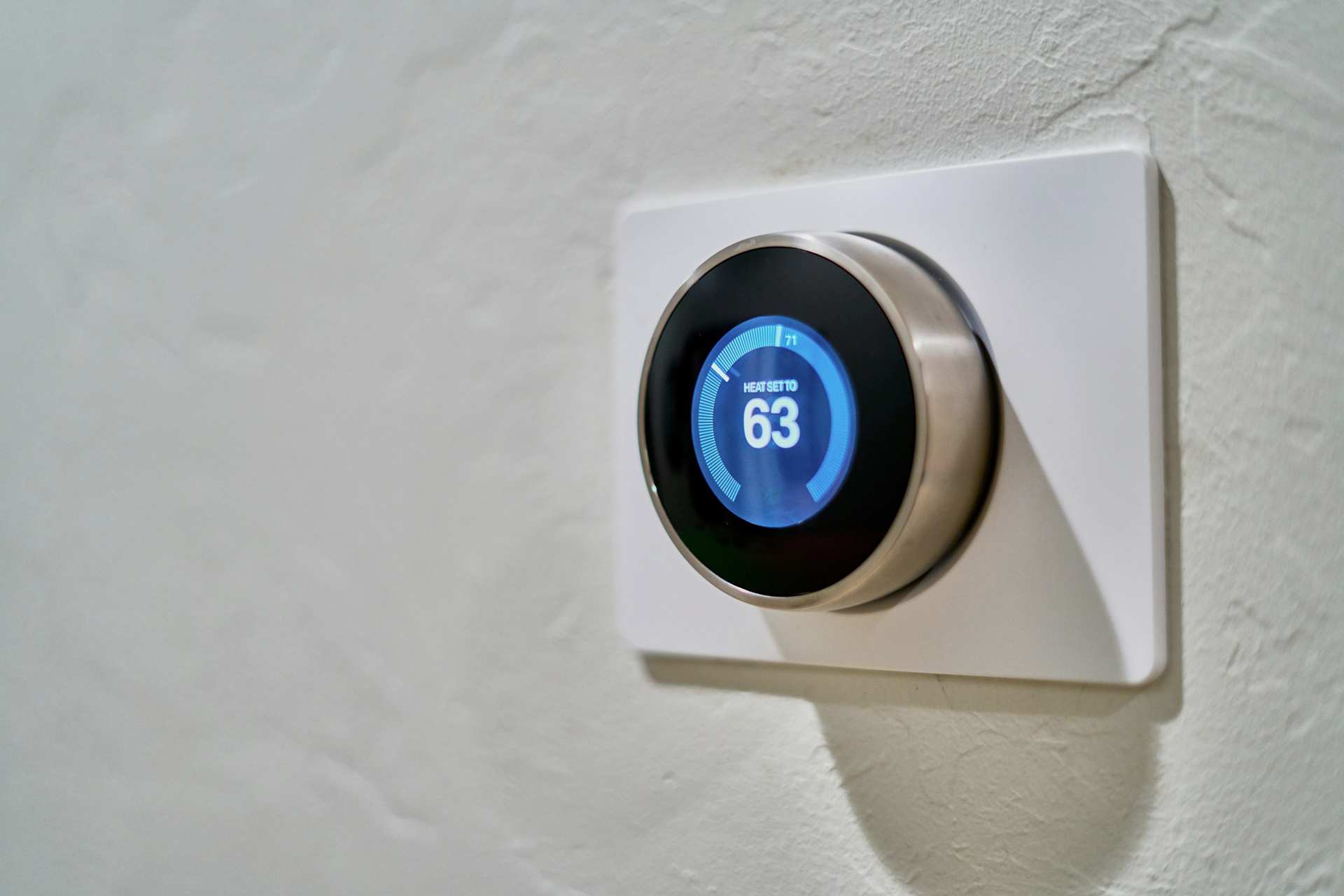Round smart thermostat mounted on a pale wall