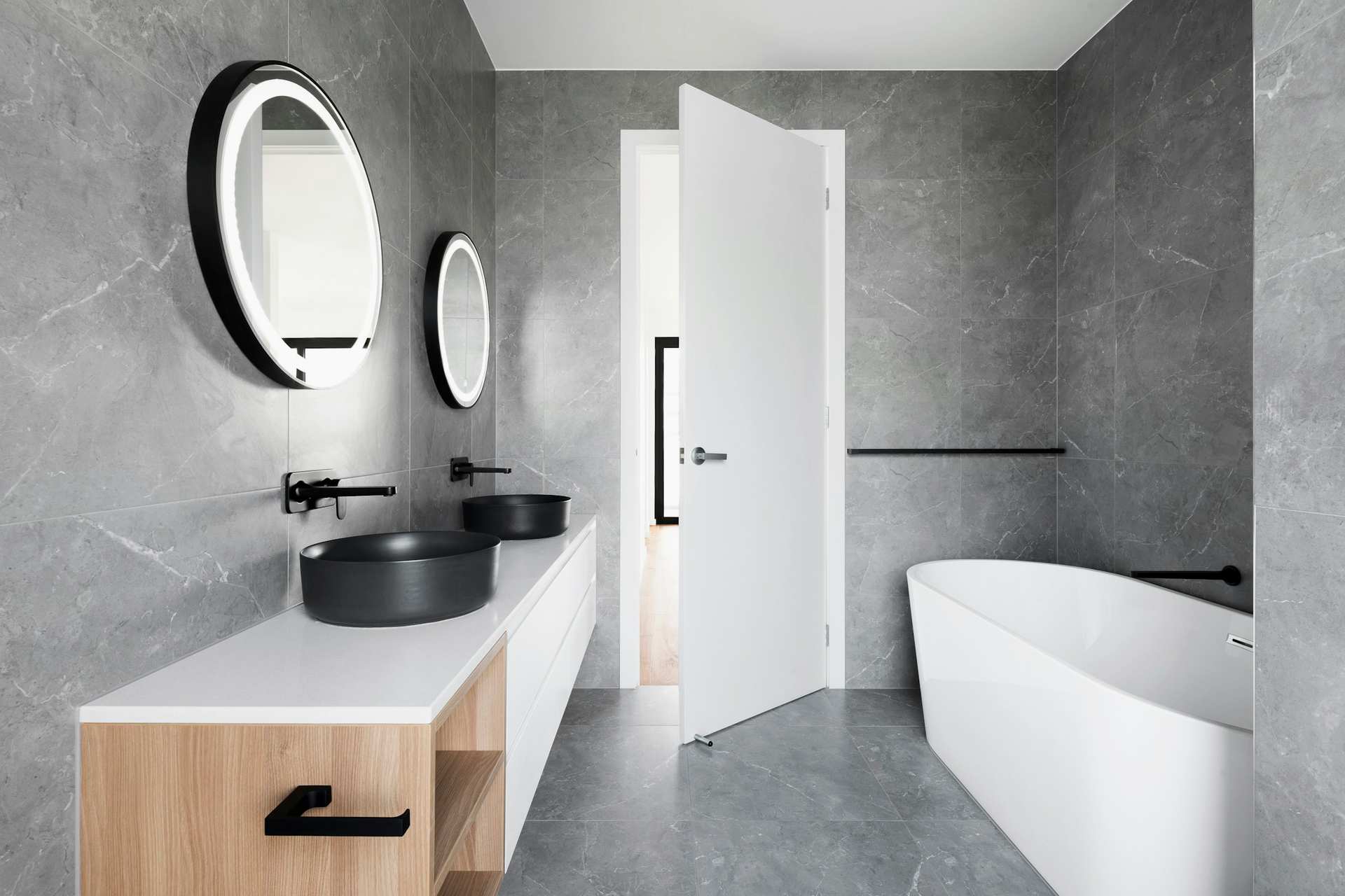 Grey stone bathroom with a vessel sink, black fittings and a freestanding tub